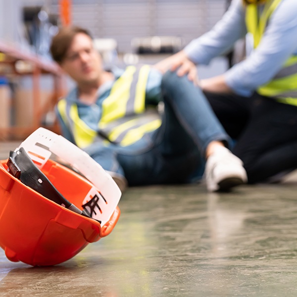 A man seated on the floor beside a hard hat shows a slip-and-fall accident in Southern California.